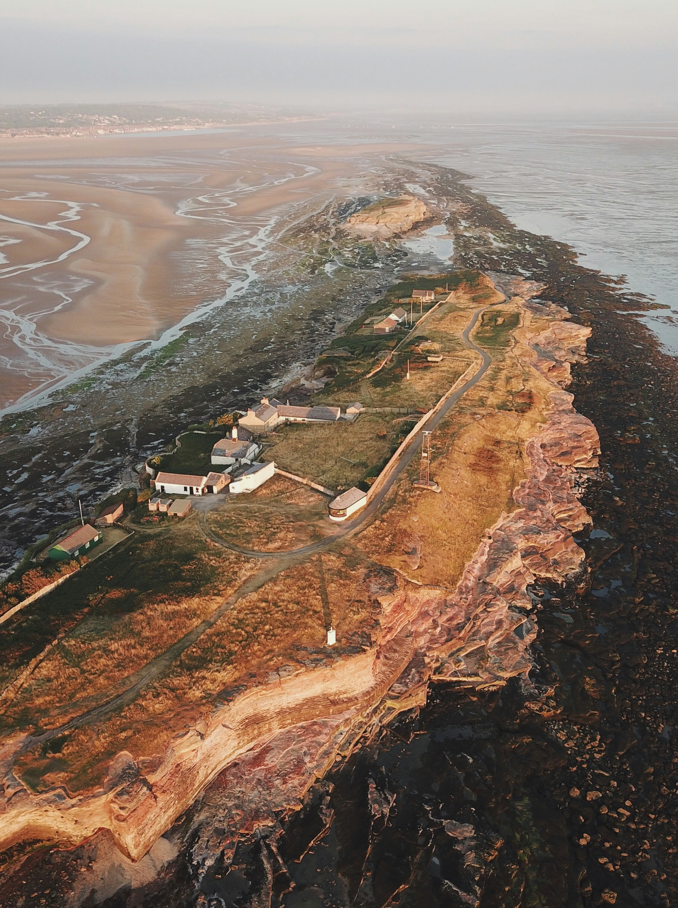 Aerial view of Hilbre Island in the Dee Estuary showing the red sandstone cliffs, buildings, and surrounding sand at low tide