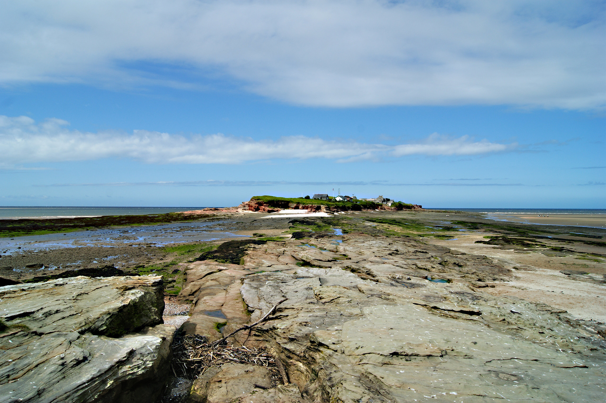 Hilbre Island viewed across exposed sandstone rocks at low tide in the Dee Estuary, Wirral