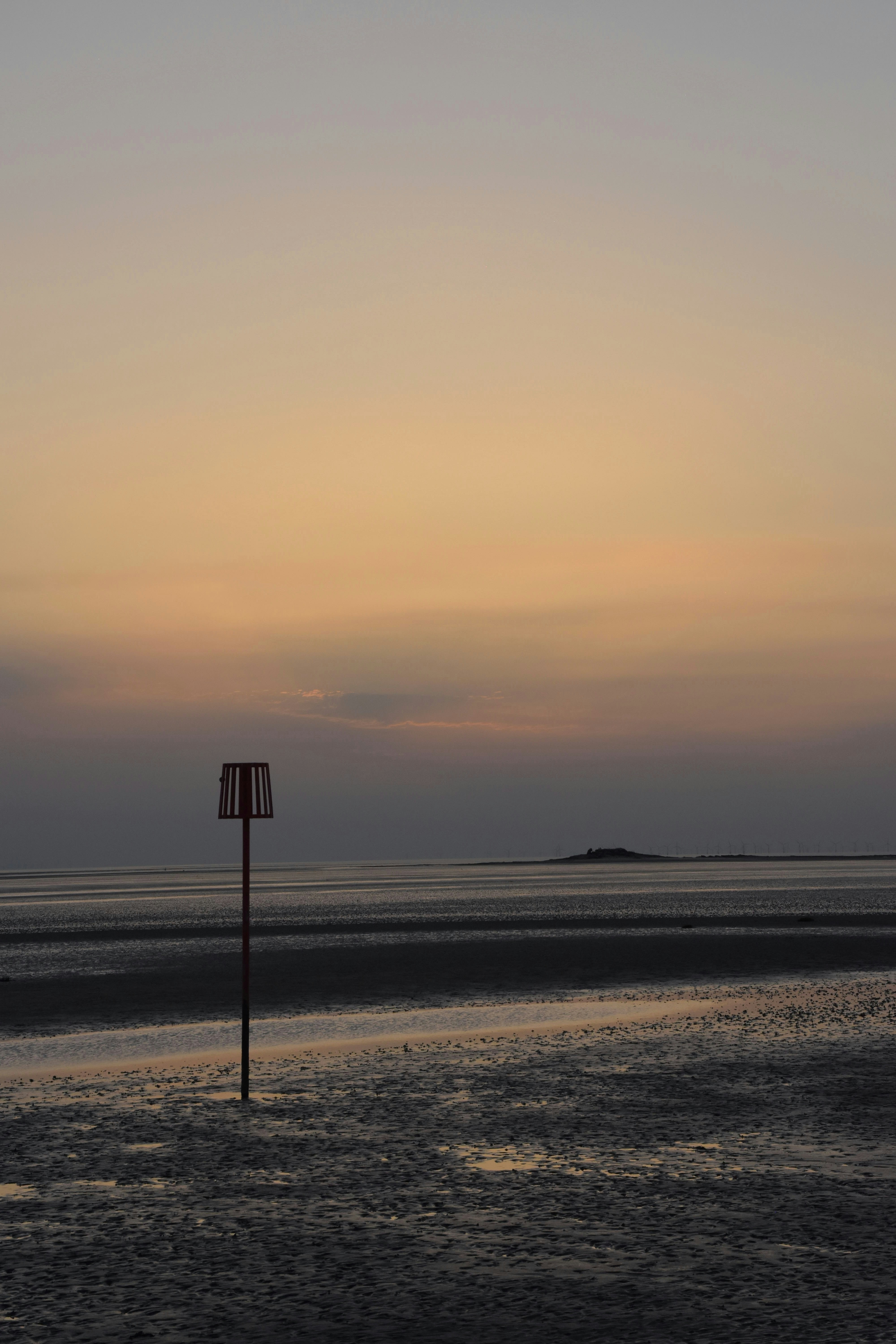 Low winter light over the Dee Estuary sand flats near Hilbre Island, with a marker post and golden sky
