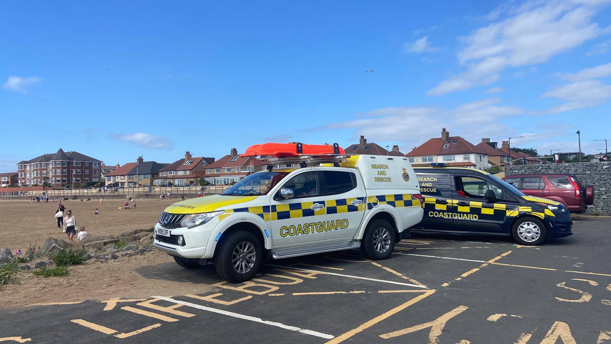 Two HM Coastguard rescue vehicles parked at the edge of a Wirral beach, both deployed to a tidal incident